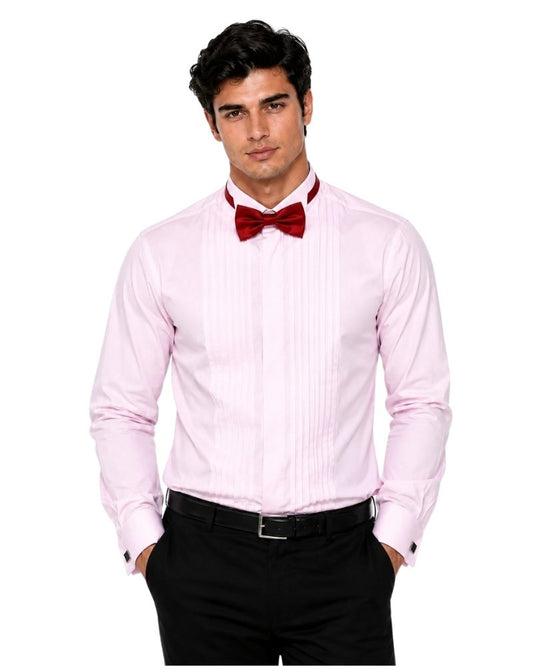 Man wearing a light pink dress shirt with a red bow tie and black pants on a white background