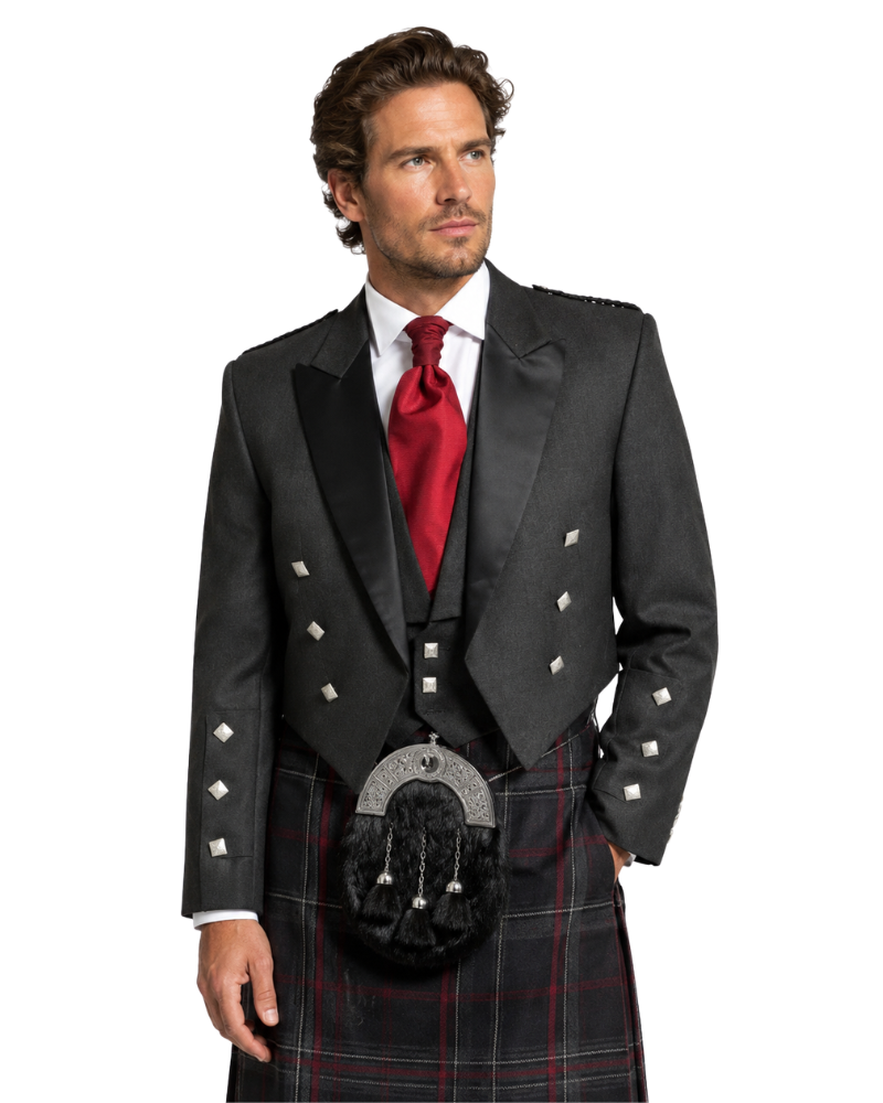 Man wearing a traditional Scottish kilt with a black jacket and red tie on a white background