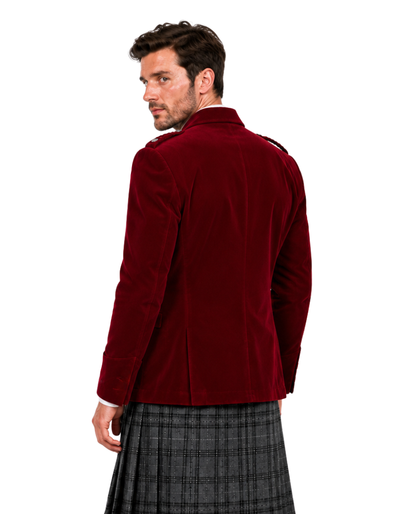 A man shown from the back wearing a deep burgundy velvet blazer over a gray and black plaid kilt, photographed against a solid white background.